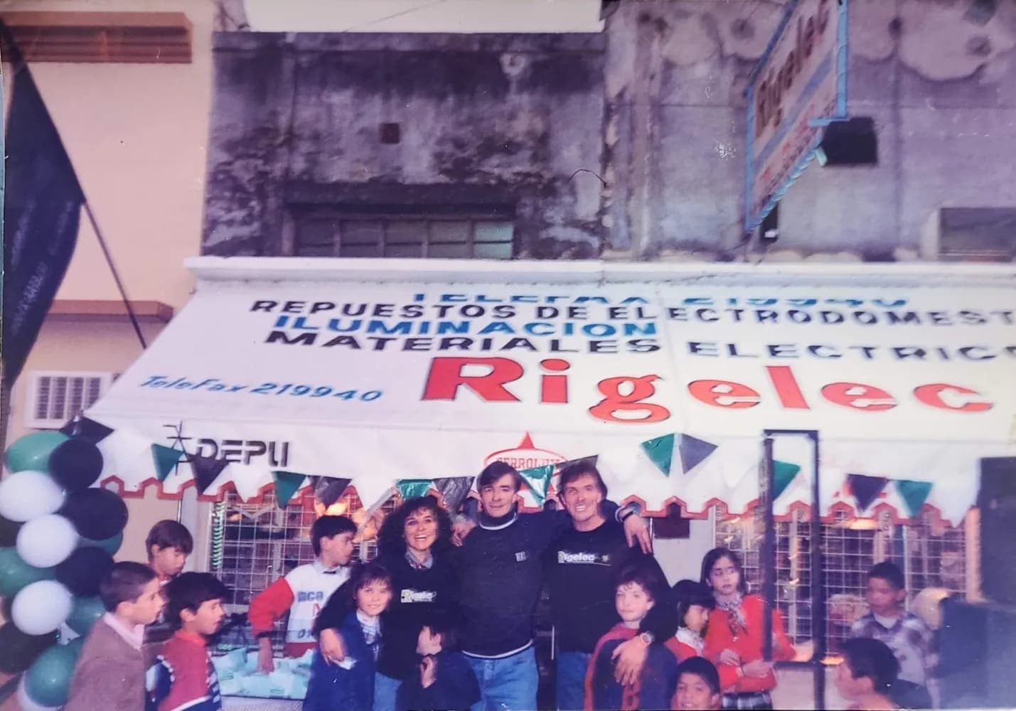 Un grupo numeroso posando frente al local original, decorado con banderines