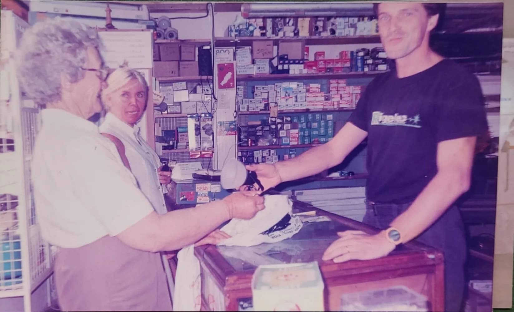 Atención en el mostrador del local, con las estanterías de productos detrás